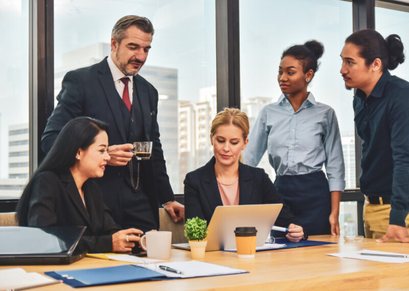 A marketing team meeting around laptop