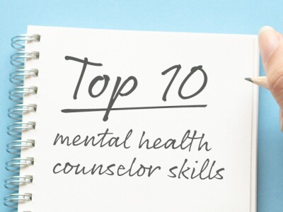 Hand of a woman writing in notebook; Top 10 mental health counselor skills