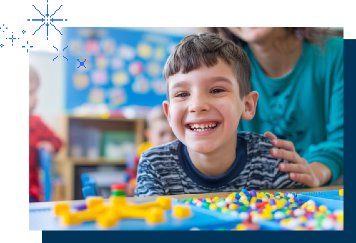 A close-up of a smiling autistic boy with a teacher behind him.