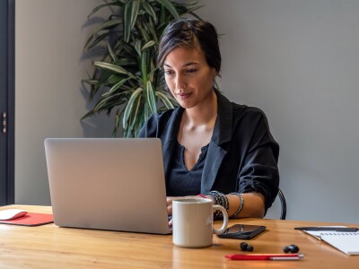 Young woman working online at home with laptop and documents