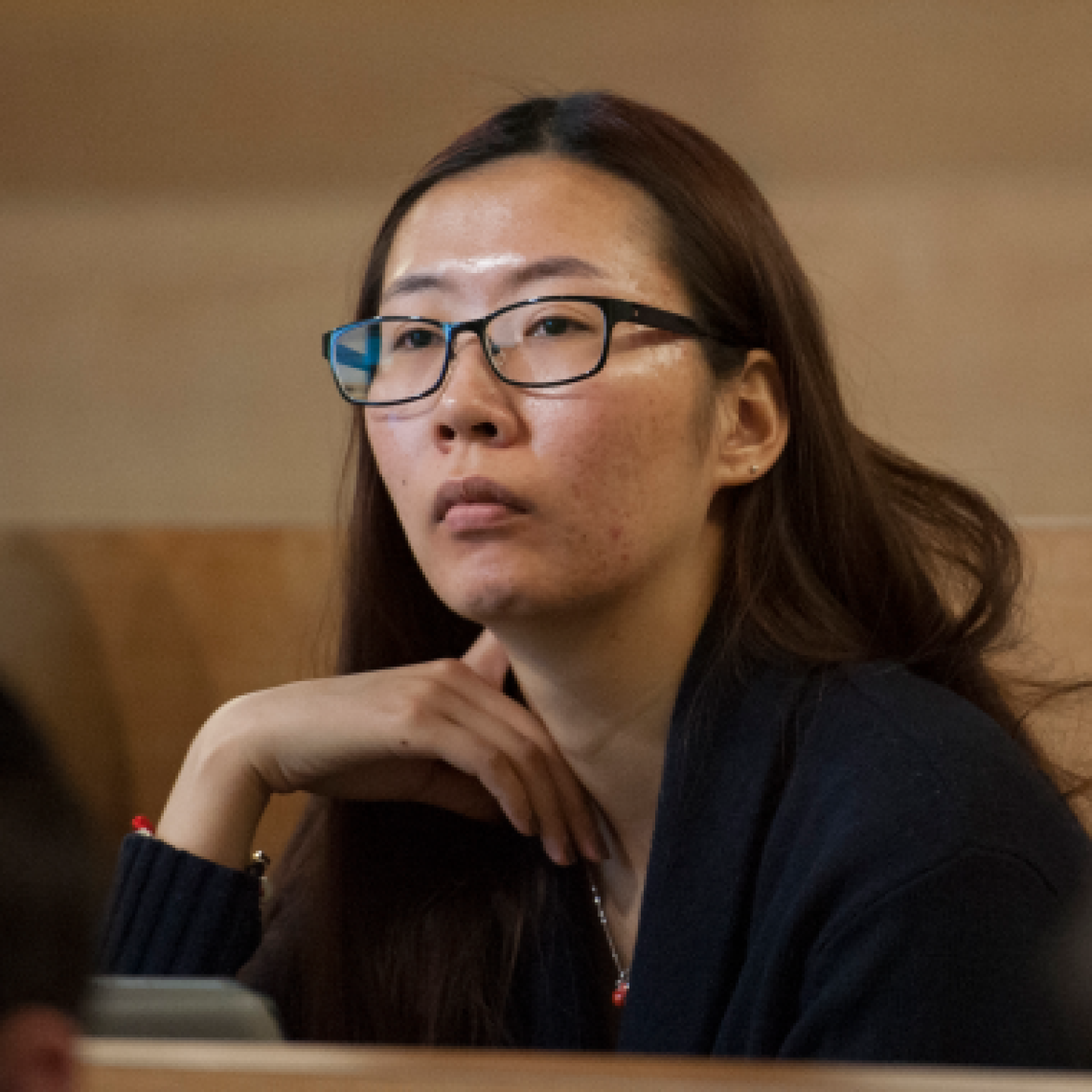 A close-up of a female Yeshiva University student listening to a professor's lecture.