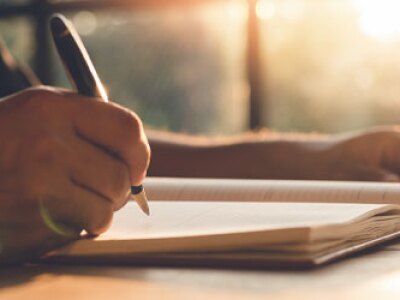 Hand writing in journal on a desk