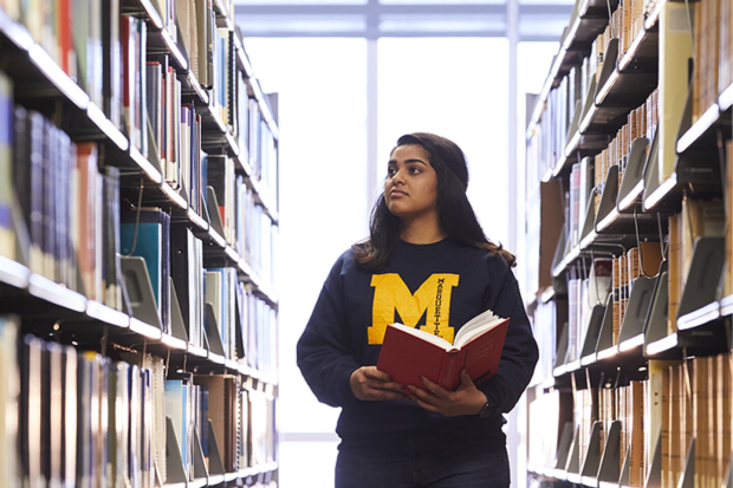 Marquette student walking through the library stacks