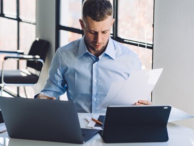 Businessman reviewing documents while using a laptop