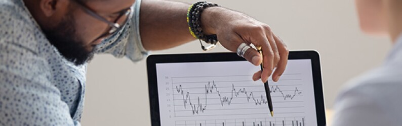 Two people examine graph data on a laptop screen