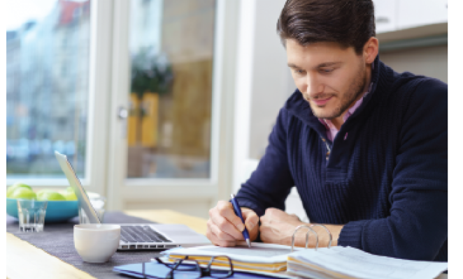 caucasian man in sweater working in front of computer