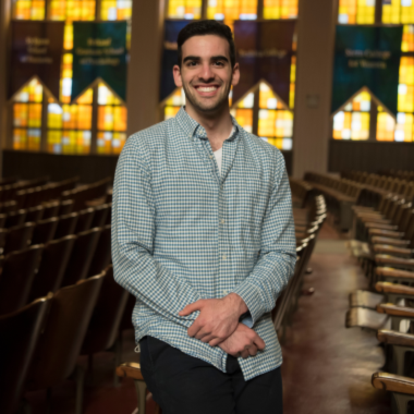 A male Yeshiva University student is smiling while standing in the campus temple.