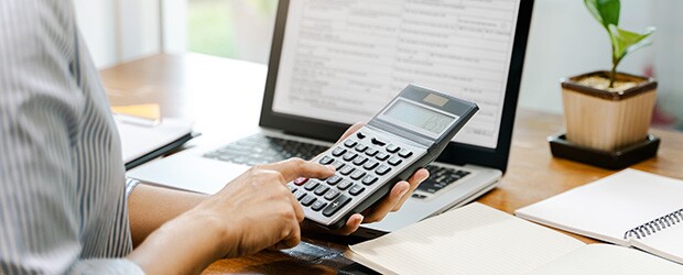 Accountant calculating net income formula at desk with calculator