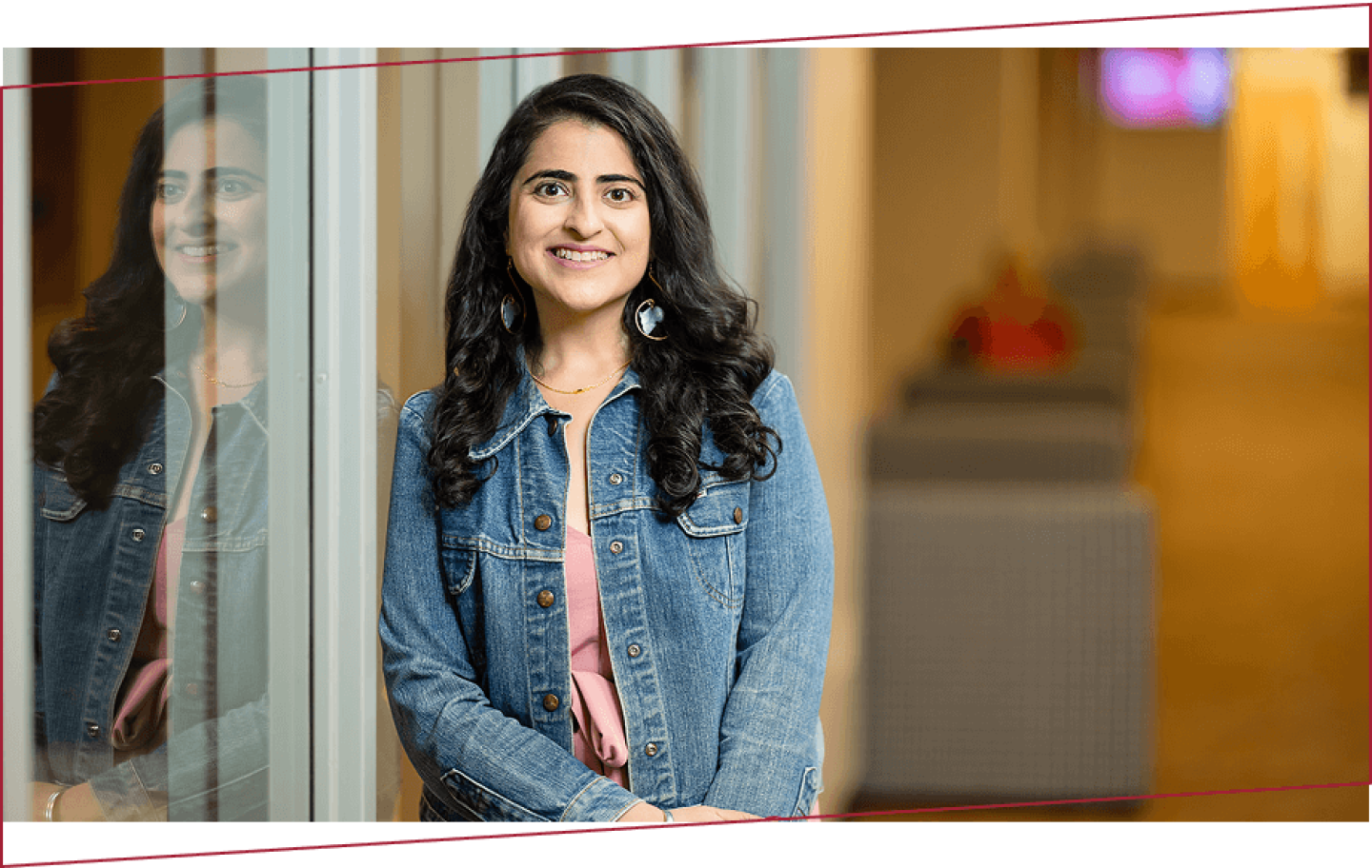 Woman in denim jacket smiling in campus building