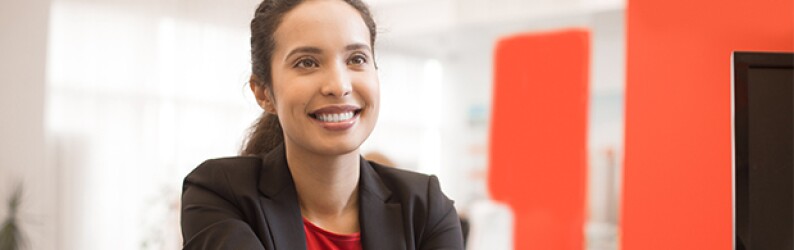 woman in red shirt black jacket shaking hands red wall to the right