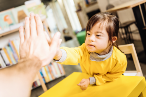 Dark eyed sunny child giving high five to her teacher