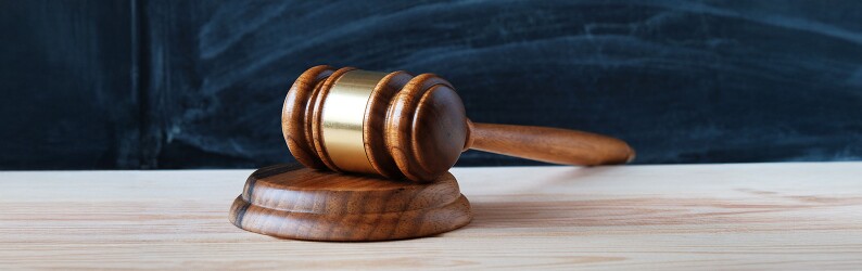 Judge's gavel on a desk in front of a blackboard