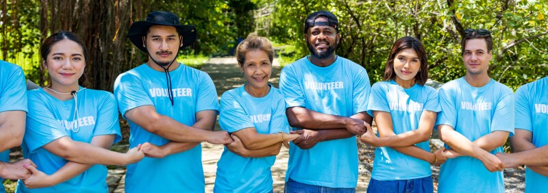 Volunteers holding hands in a chain facing the camera smiling