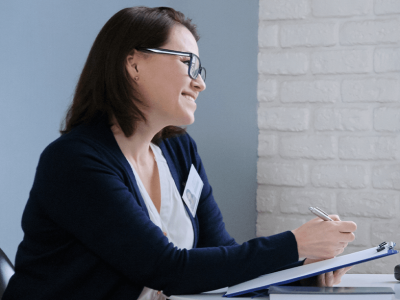 Female counselor speaking with teenage girl while writing on a clipboard