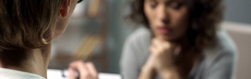 Young depressed woman talking to female counselor about her mental health during session.