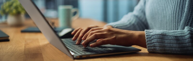 Close up on hands of a female working on a laptop in her living room