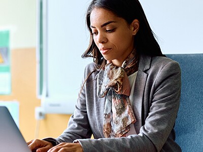 Teacher working on her laptop in classroom at school