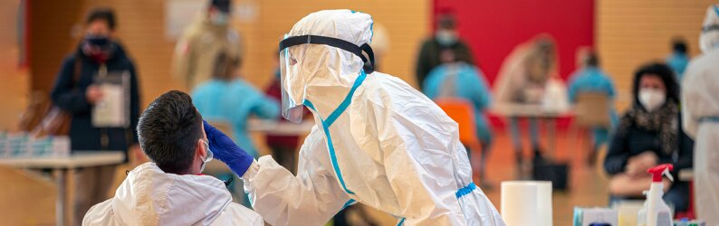 Health workers in protective suits are engaged in salivary and nasal tests inside a public gym.