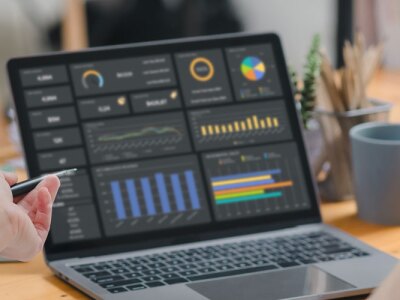 An accountant team are analyzing data charts, graphs, and a dashboard on a laptop screen in order to prepare a statistical report.