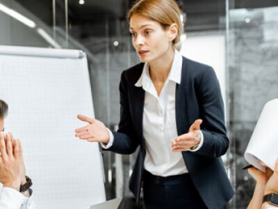 Woman in meeting talking to frustrated colleagues