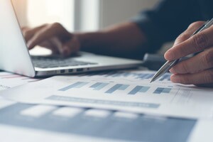 Businessman using computer to review balance sheets.
