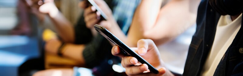 Group of young adult friends using smartphones in the subway