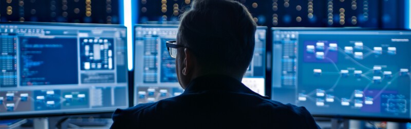 Professional IT Programer Working in Data Center on Desktop Computer with Three Displays.