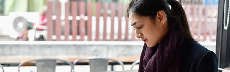 woman-at-coffee-shop-working-on-laptop-writing-notes