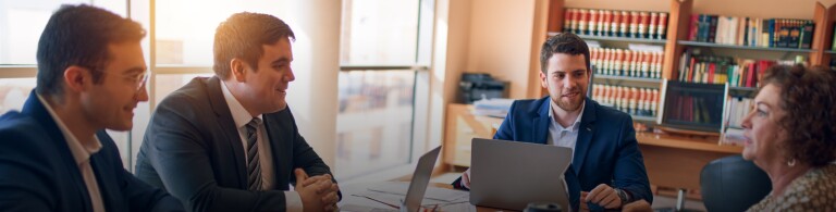 a group of professional conduct a meeting in a law office while working on laptops