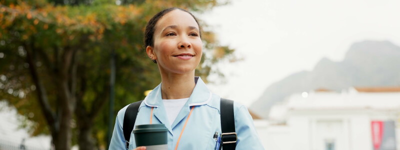 An allied health professional smiles while standing outside her place of employment
