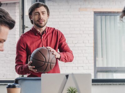 Young male sports manager discusses business strategies with male colleagues.