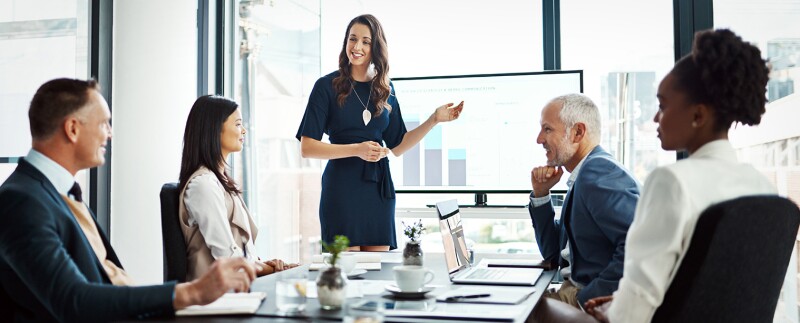 Professional woman presenting data insights on a screen to a group of colleagues