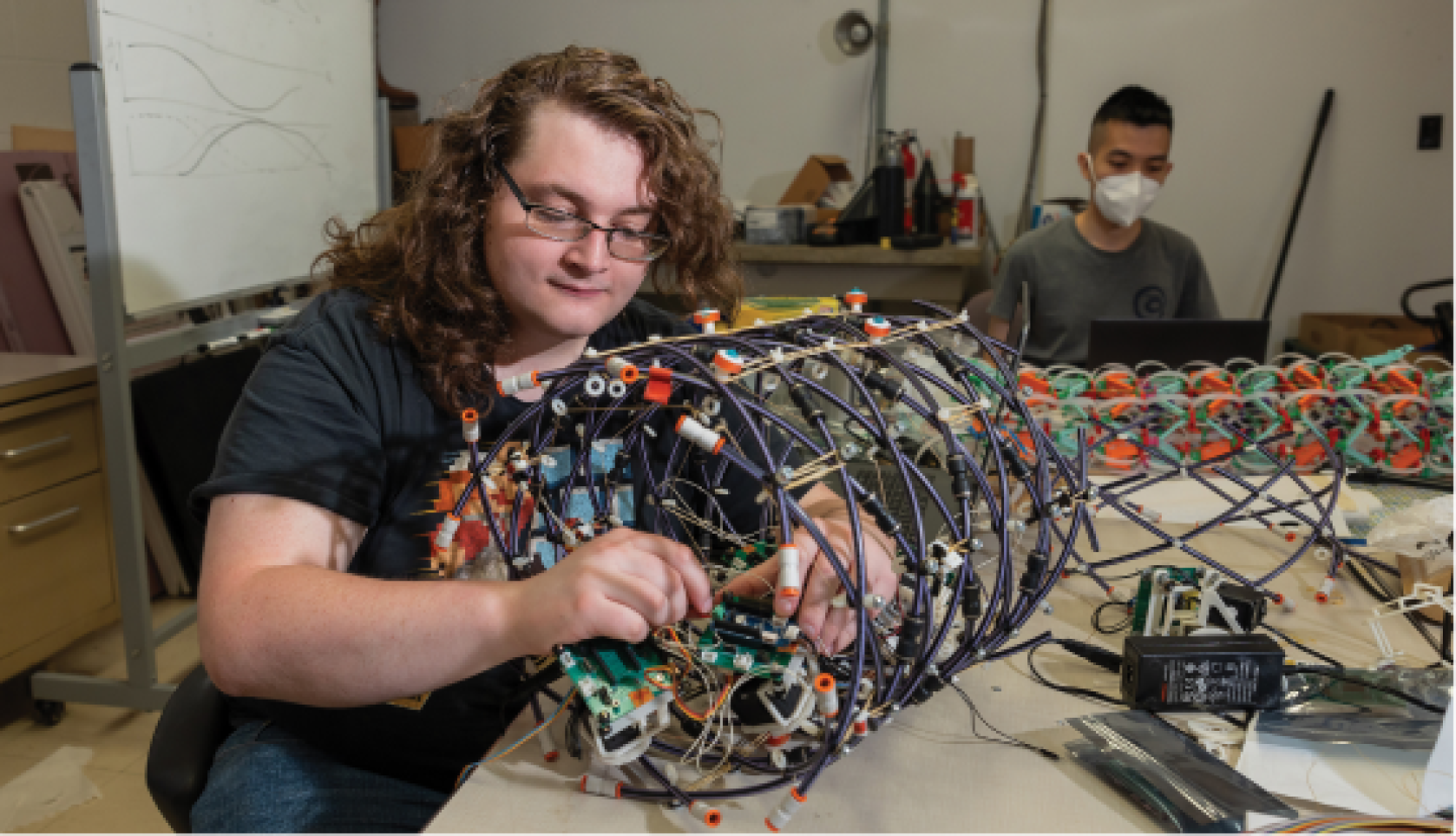 A male CWRU mechanical engineering student working on device in a fabrication workshop.