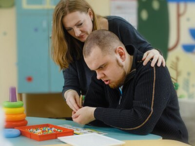 A female psychologist works with an adult boy with autism in the office.