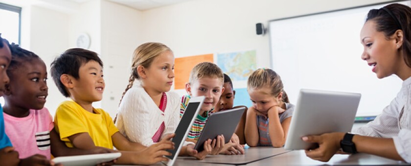Teacher-using-tablets-to-teach-younger-students
