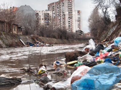 Landfill overflowing into river in an urban environment