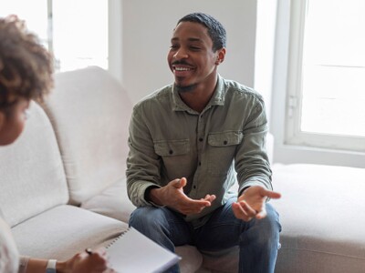An African American counselor talking with a client in a bright, comfortable therapy room