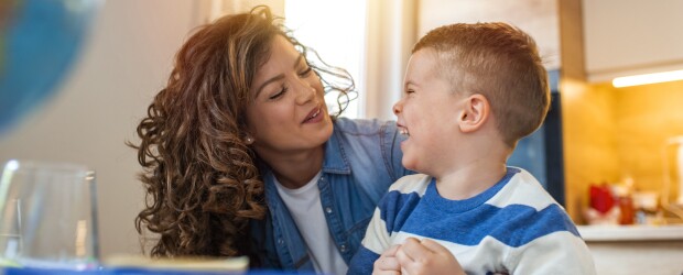 Caregiver and child laughing together in kitchen