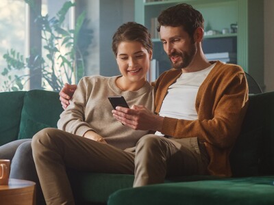 Couple using a smartphone to shop while sitting on a couch