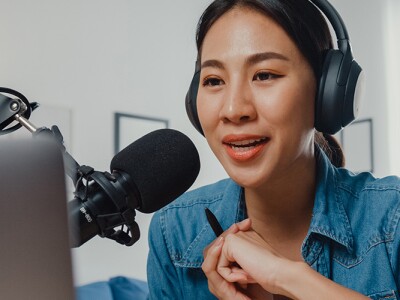 Female podcaster make audio podcast from her home studio.