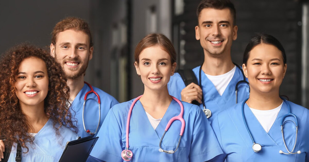 Nurse wearing PPE gear standing confidently in front of a modern healthcare facility entrance.