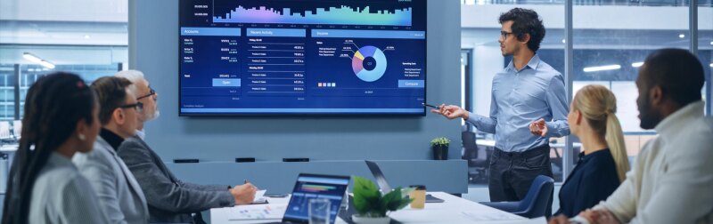 Latin Businessman Talks, Uses Wall TV to Show Company Growth with Big Data Analysis, Graphs, Charts, Infographics.