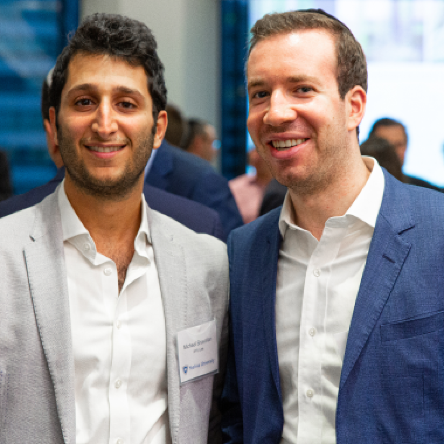 A close-up of two male Yeshiva University real estate students smiling at an event.