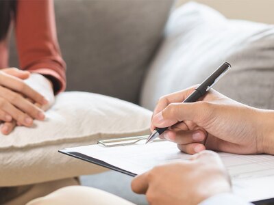 Counselor holding clipboard and pen in therapy session with patient