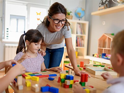 Teacher with glasses with kids at table