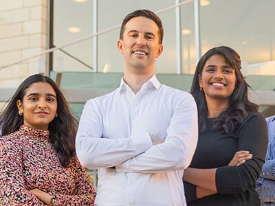 A group of SCU Leavey student stand outside in front of the campus commons building.