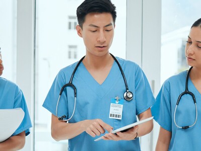 Three nurses discussing patient information, with one using a tablet to explain details.