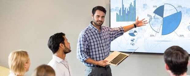 man in plaid shirt presenting pie chart to group