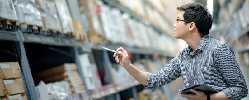 Man doing stocktaking warehouse by using digital tablet