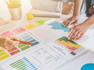 Hands of people collaborating over graphs and charts on a table
